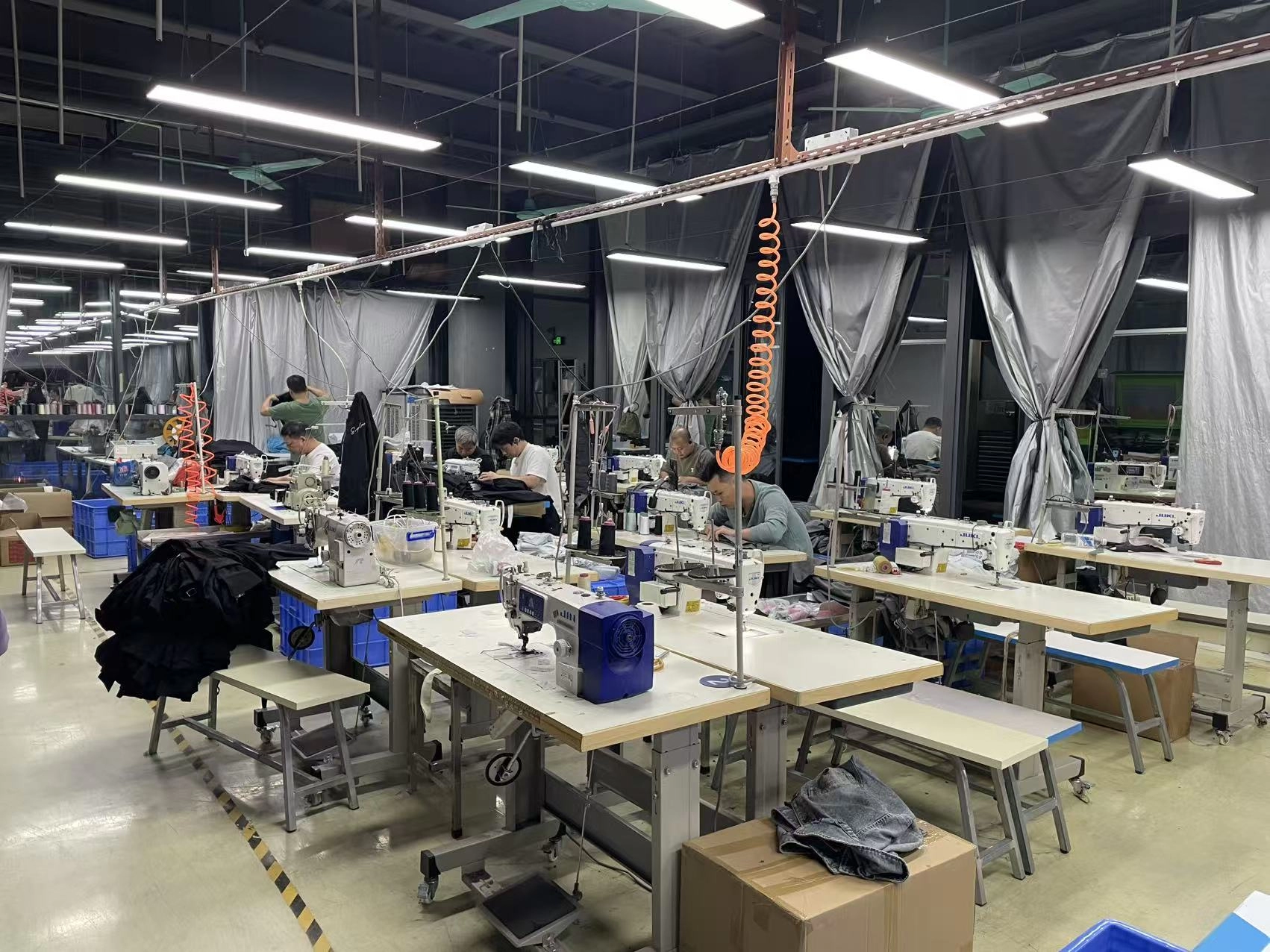 Rows of sewing machines and rolls of fabric on a garment production floor