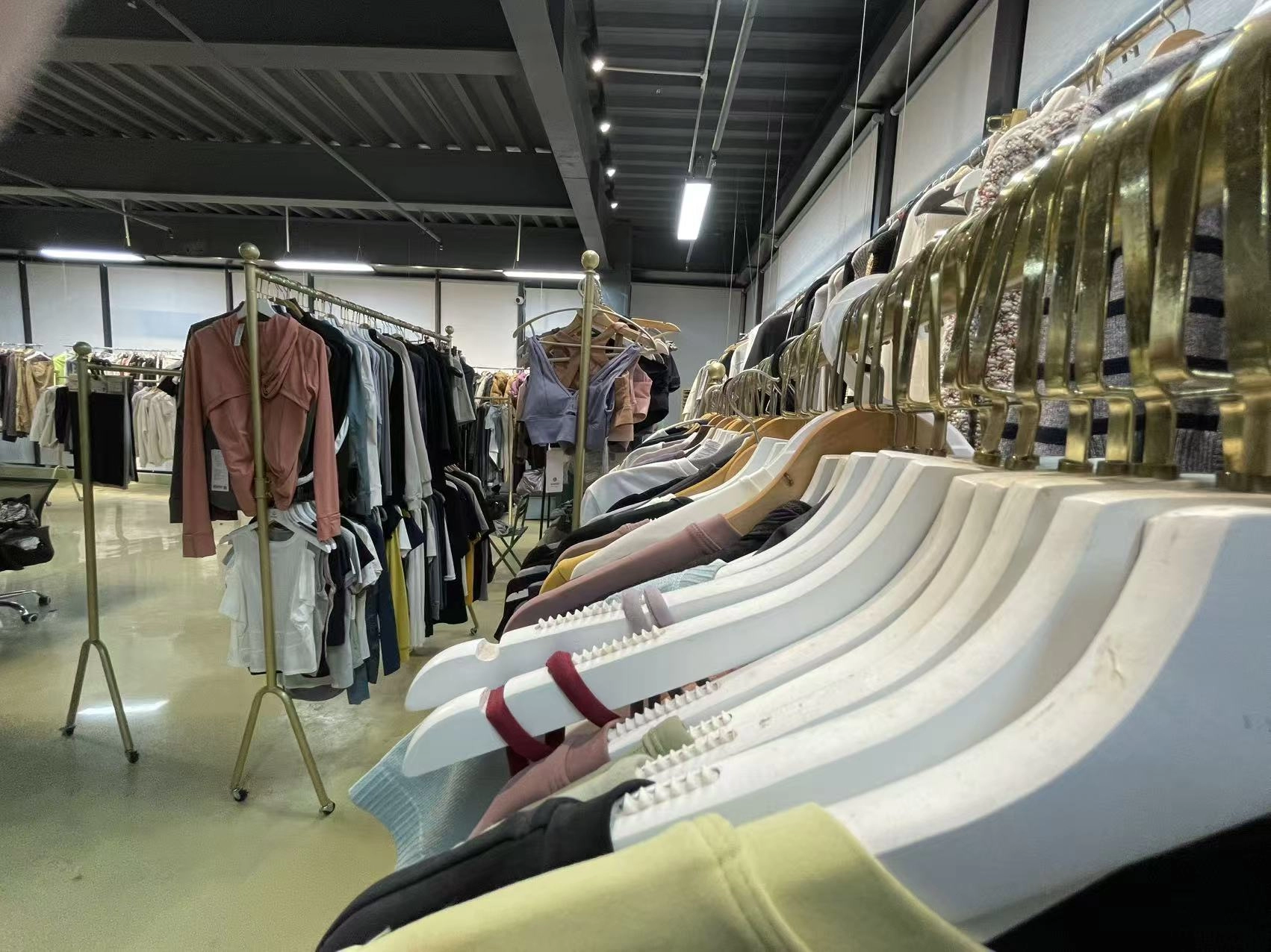 Garment rails and folded knitwear stacked in a garment factory showroom