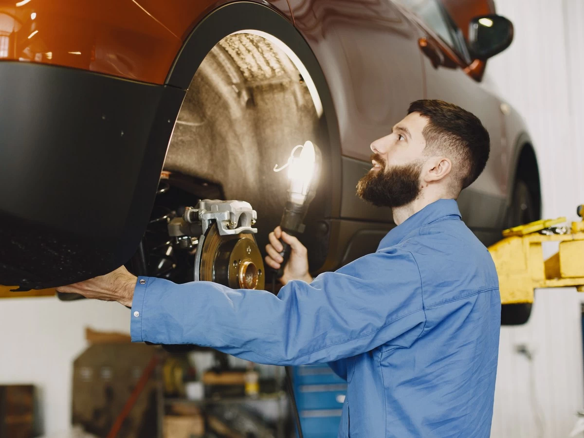 Technician Checking Brake Disc With Flashlight