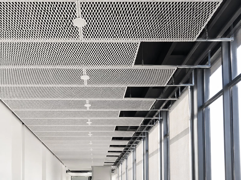 White expanded metal mesh panels suspended in an open ceiling grid