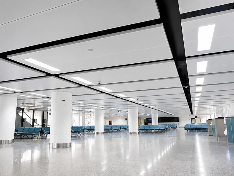 Large white aluminum ceiling panels with integrated lighting in a terminal