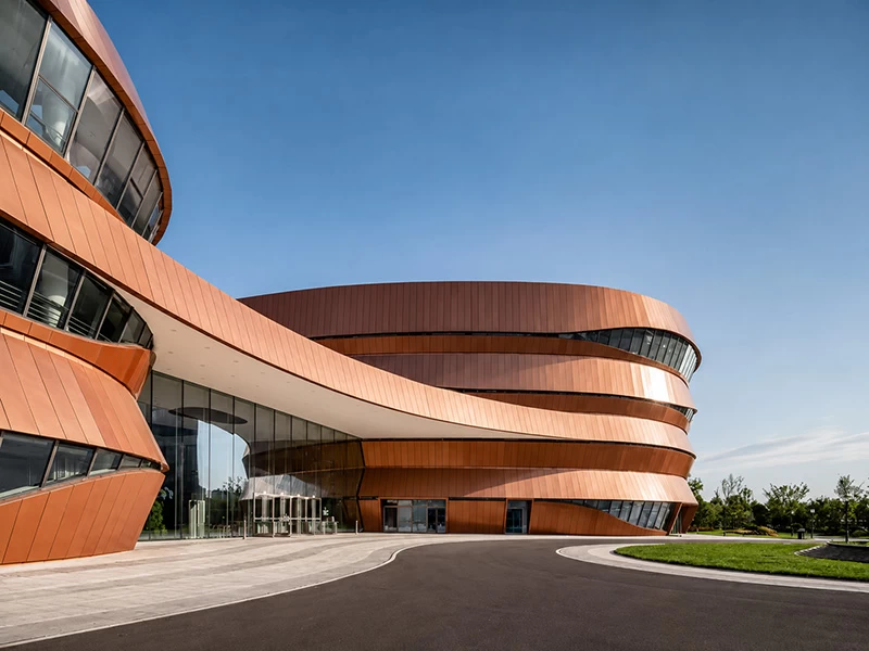 Copper-look curved aluminum cladding wrapping a landmark cultural building