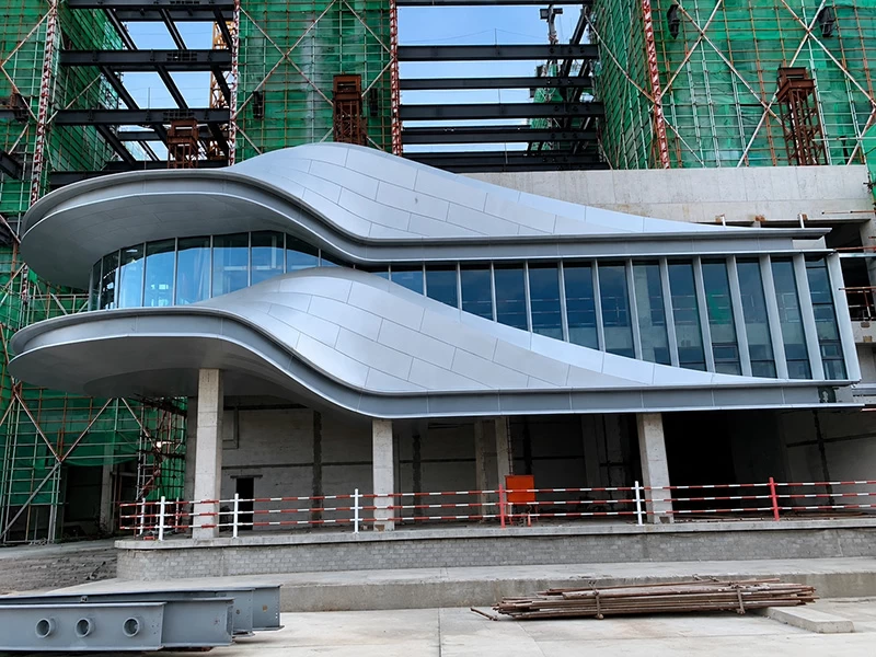Curved silver aluminum cladding panels on a freeform building entrance