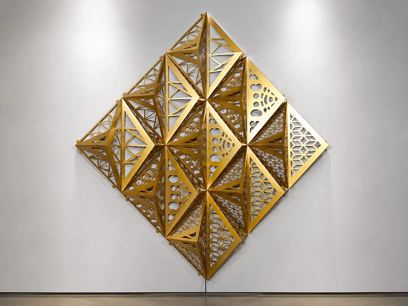 Golden three-dimensional perforated aluminum geometric wall installation