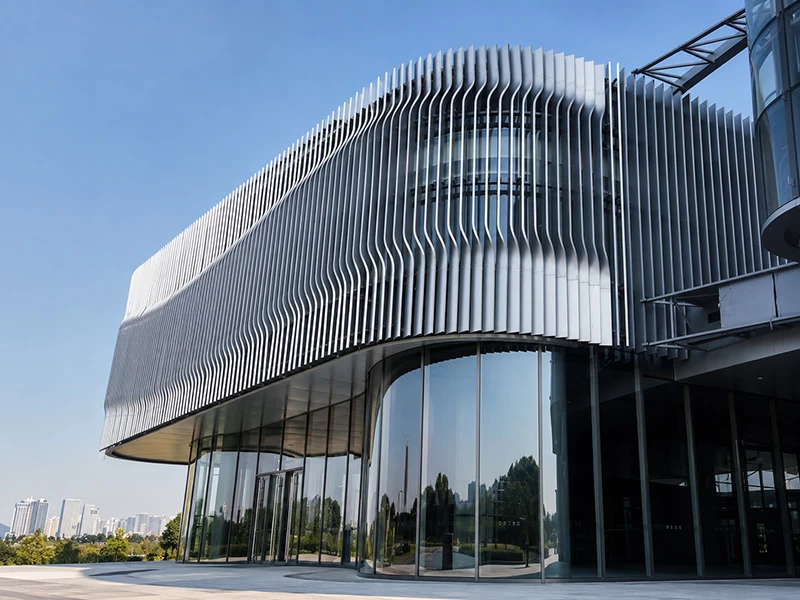 Curved silver aluminum louvers wrapping a rounded glass building facade