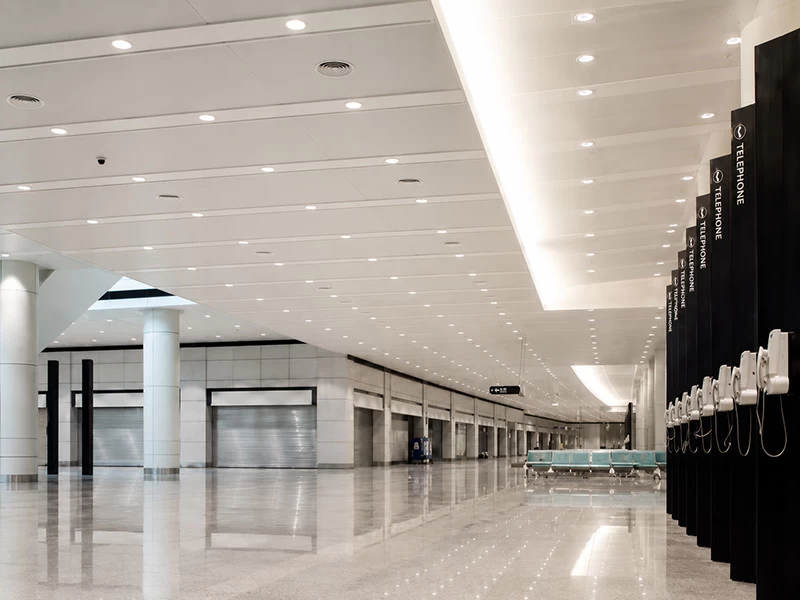 White linear aluminum strip ceiling across a large public interior