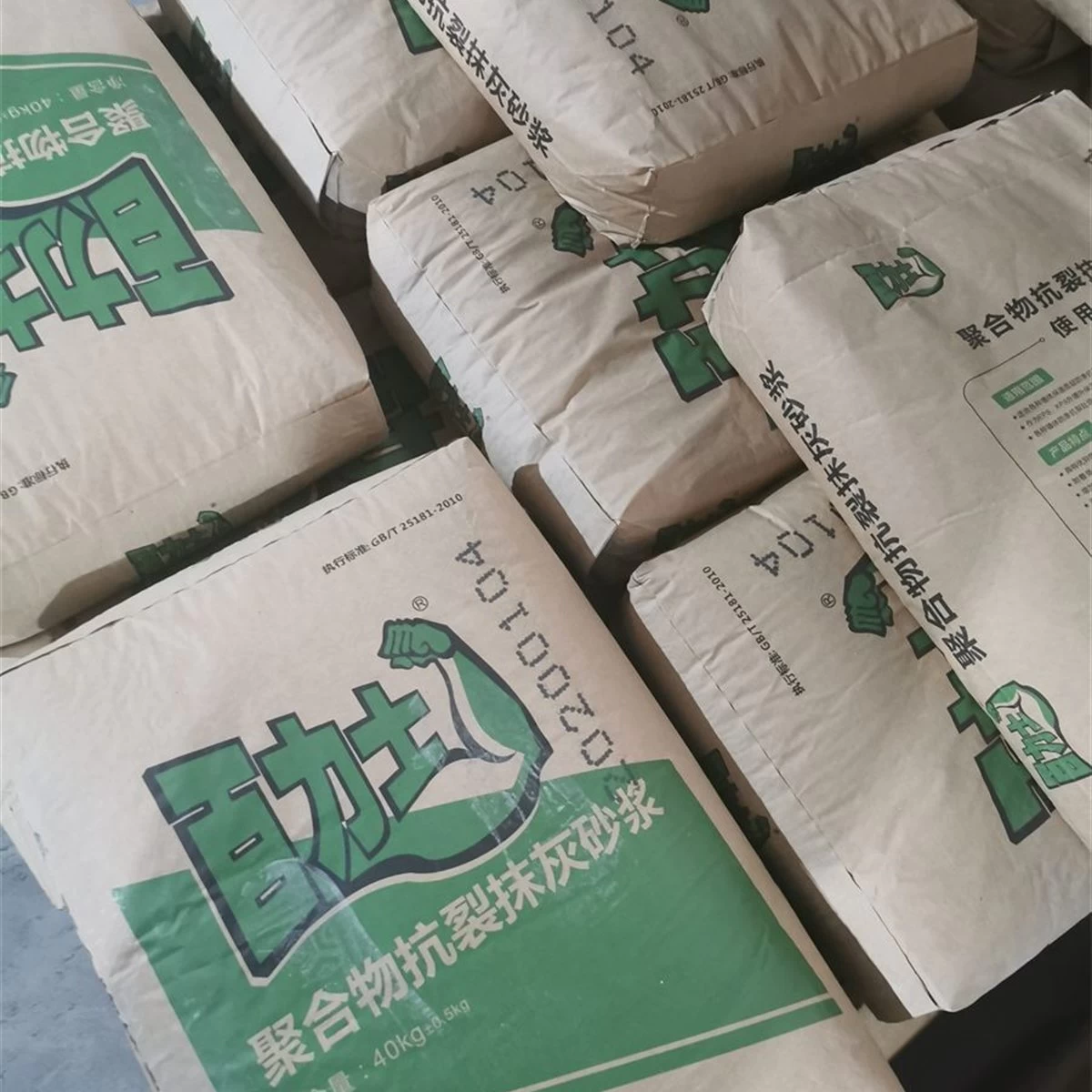Green bags of polymer anti-crack plastering mortar in storage square primary view