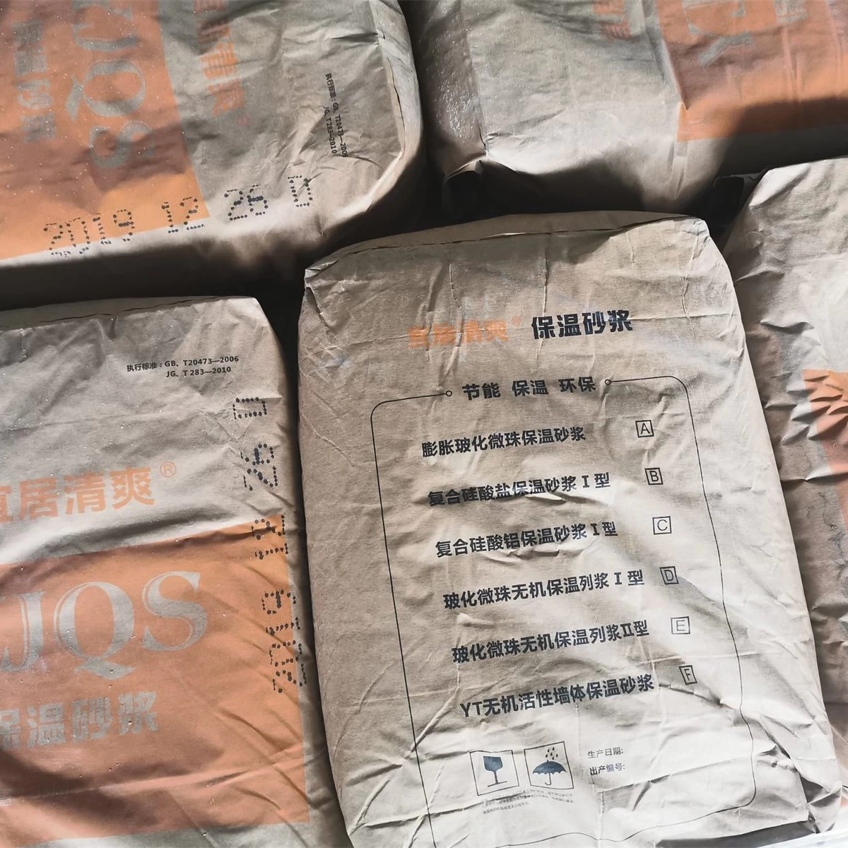 Palletized bags of thermal insulation mortar in production area square primary view