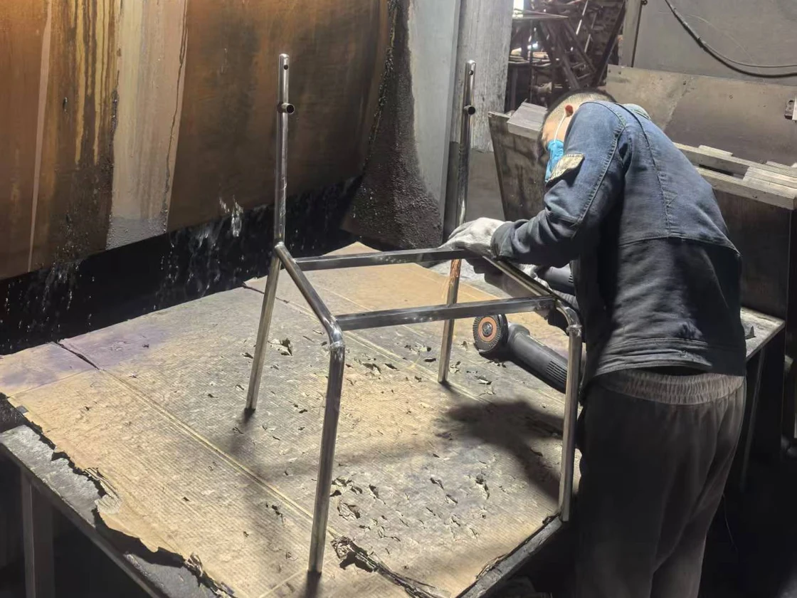Worker handling a metal chair frame at a workshop bench