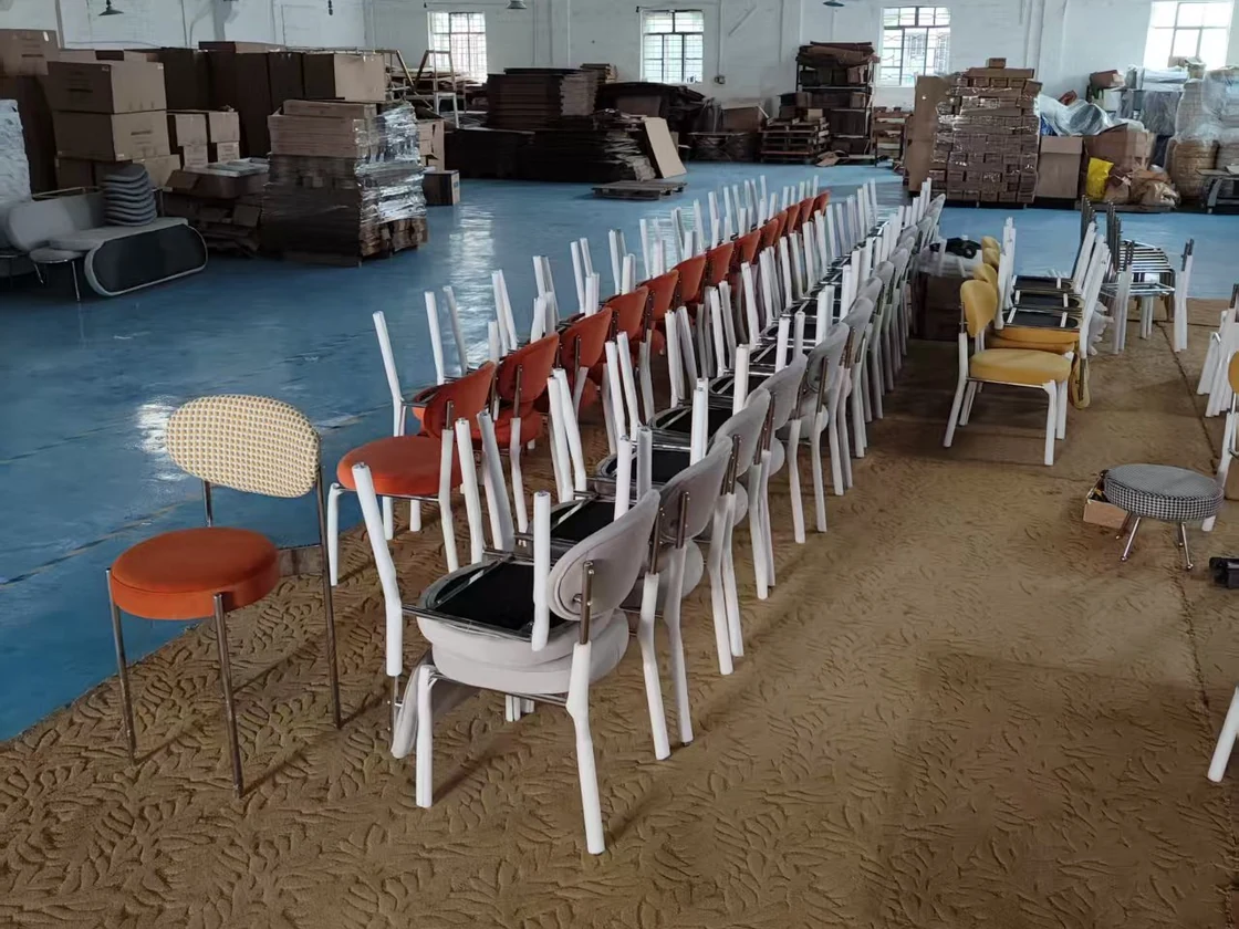 Different dining chair designs and colors arranged in rows in the workshop